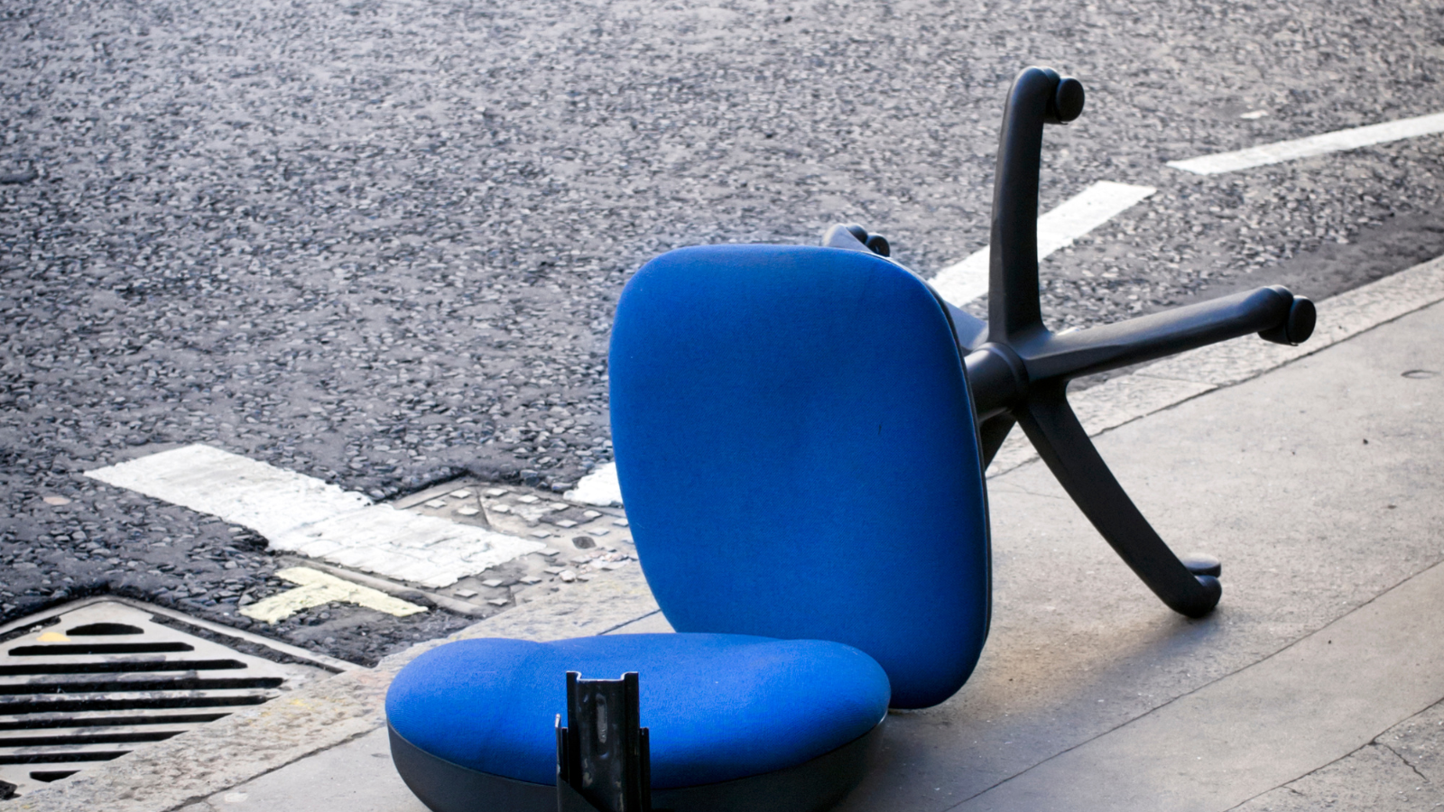 Broken office chair left on the pavement.